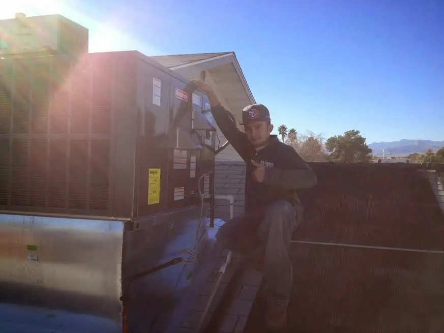 HVAC technician performing Air Duct Cleaning on a rooftop unit in Tracy